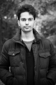 Photo of Massimiliano Saltori as Guy reading at the counter