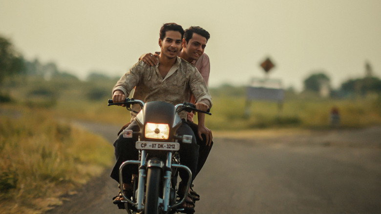 Two men walking along a deserted highway, one carrying the other on his back, their shadows stretching long in the late afternoon light.