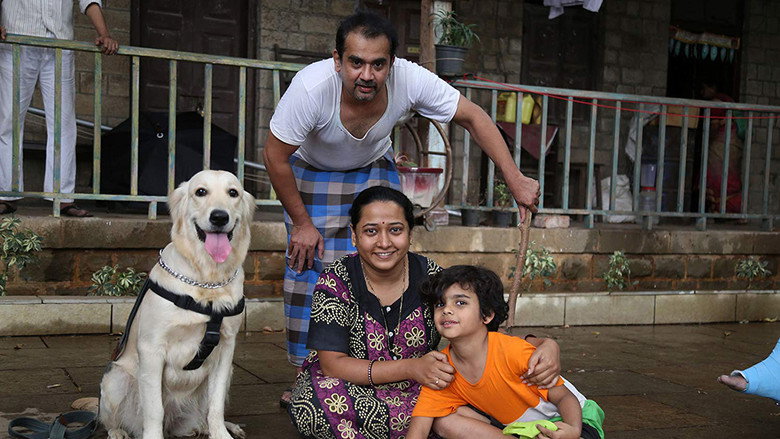 A crowded Mumbai chawl balcony, laundry flapping in the breeze, neighbors leaning over railings to gossip