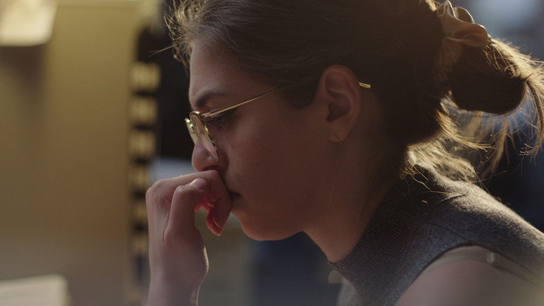 A dimly lit interrogation room, the camera angled to show the stark contrast between the officer’s calm demeanor and the young woman’s visible distress.