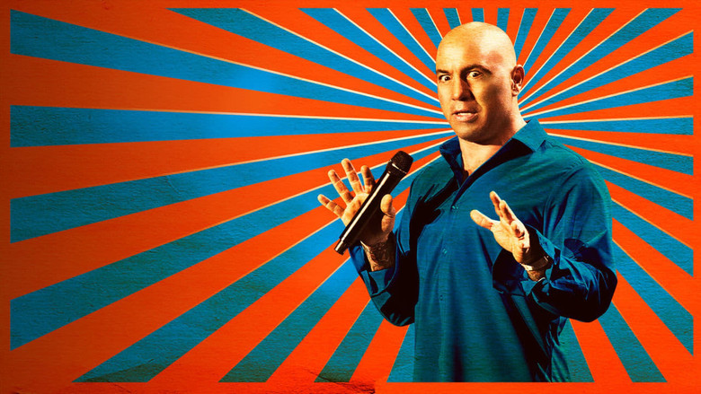 Joe Rogan on stage, mid-gesture, under warm stage lights