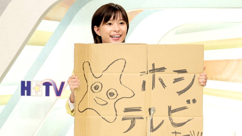 Hanako, wide-eyed and grinning, stands in the middle of a bustling newsroom, surrounded by colleagues who look equal parts exasperated and amused.