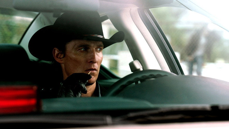 A dimly lit trailer interior, where Matthew McConaughey’s Joe Cooper looms over Juno Temple’s Dottie, his shadow stretching across the wall like a threat.