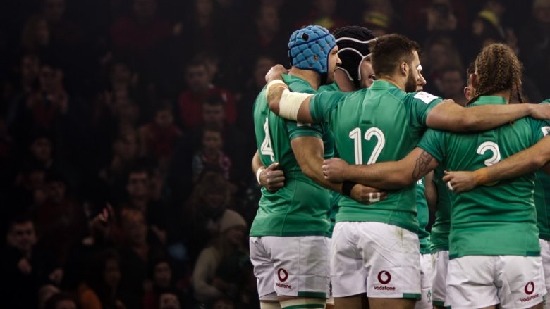 A huddle of rugby players in red jerseys, their faces tense with focus, moments before a match