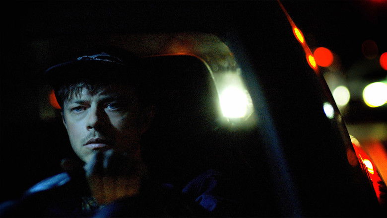 A tense, low-light shot of a hacker illuminated only by the blue glow of a laptop screen