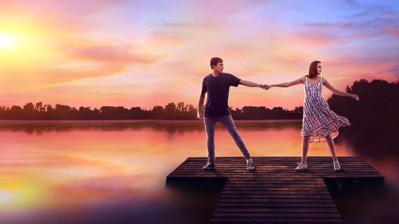 A group of teens in matching camp T-shirts stand in a circle, arms around each other, smiling under a golden sunset