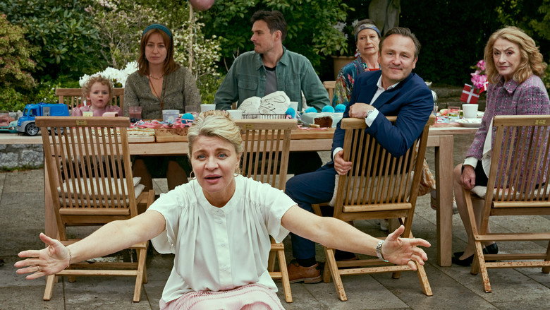 Two couples awkwardly sharing a kitchen, one holding a baby while the other stirs a pot of something suspiciously green