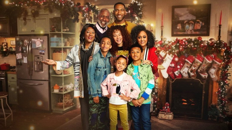 The McKellan family gathered around a Christmas tree, laughing as one of the kids holds up a handmade ornament