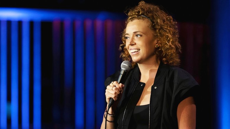 Michelle Wolf on stage, mid-laugh, arms outstretched, the spotlight catching the sweat on her forehead