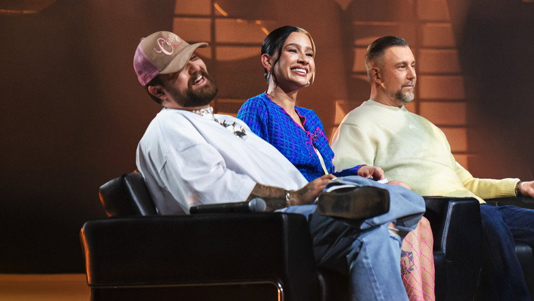 A contestant performs under neon lights, judges watching intently