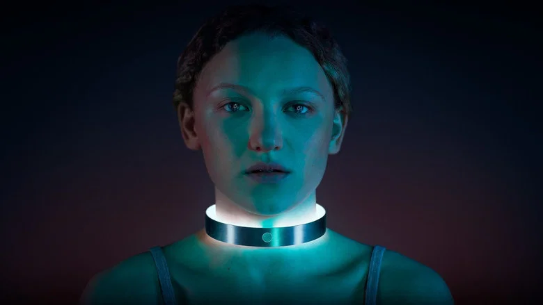 A dimly lit bedroom where Leila, a young woman with dark hair, sits hunched over a glowing computer screen, her face half-lit by the monitor’s eerie blue light.