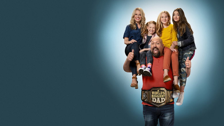 The Big Show looms over his family in their living room, his towering frame making the furniture look like dollhouse pieces.