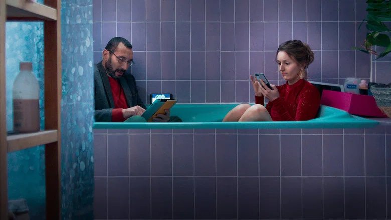 Two women sit on a couch, backs to the camera, staring at a blank wall where a TV used to be
