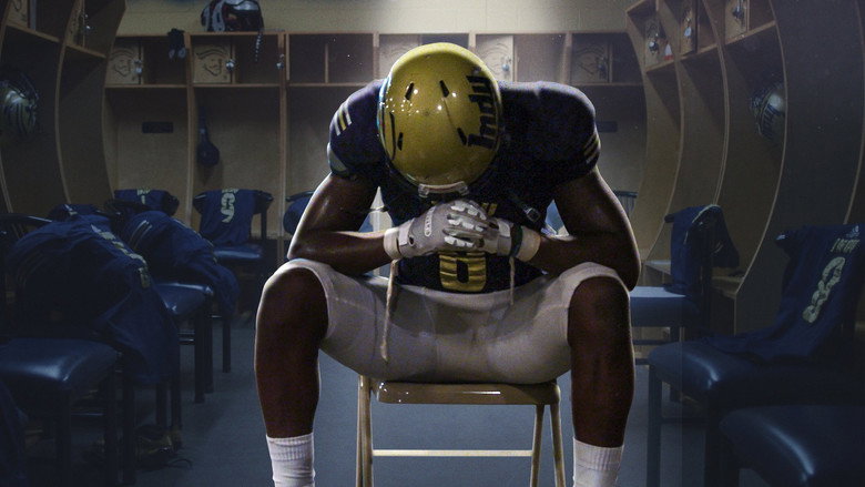 A player in full pads stands alone on the field, his shadow stretching long under the stadium lights.