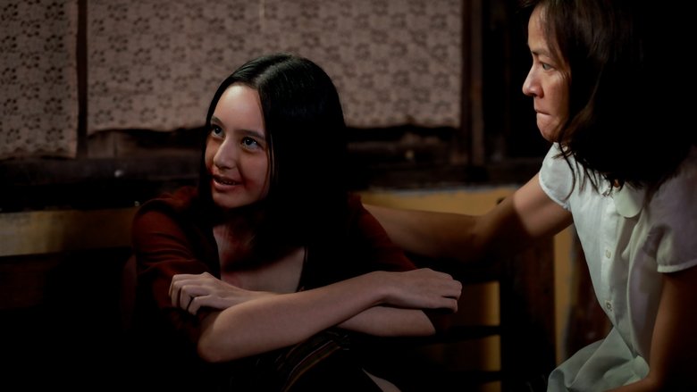 A dimly lit room where a family gathers around a possessed sister, her face half-shadowed in eerie green light