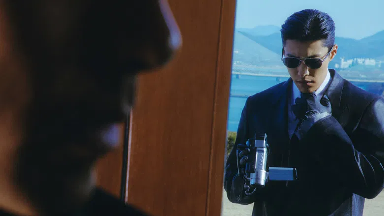 A man smoking a cigarette while looking out a window into the night