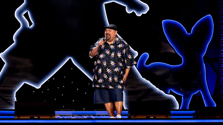 Gabriel Iglesias performing at Dodger Stadium, bathed in stage lights, with the vast empty seats stretching into the distance