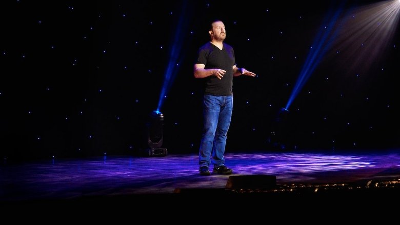 Ricky Gervais on stage, mid-joke, with a faint smirk that doesn’t quite reach his eyes
