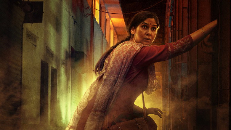 A close-up of Sheel Chaudhary, her face half in shadow, eyes reflecting a mix of exhaustion and simmering anger.