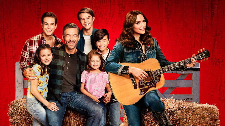 The family gathers around the kitchen table, laughter caught mid-air as Katharine McPhee’s character strums a guitar in the background.