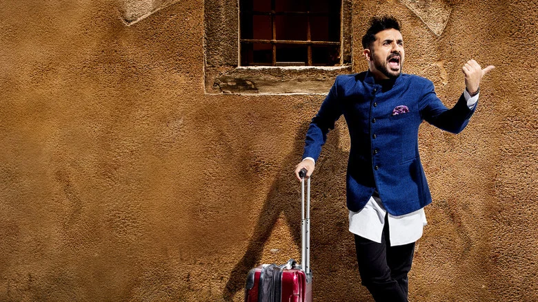 Vir Das on stage, mid-gesture, the audience blurred in the foreground