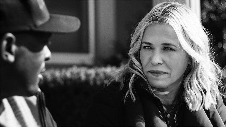 A close-up of Chelsea Handler mid-conversation, her expression a mix of amusement and self-awareness, the background blurred but warmly lit.
