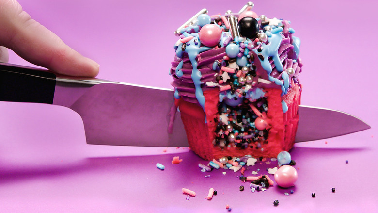 A team of bakers races against the clock, their hands moving frantically as they decorate cupcakes with precision and speed