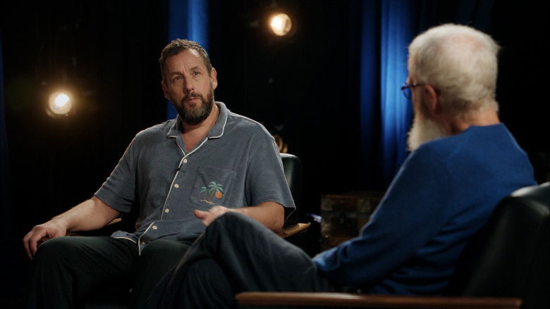 Adam Sandler and David Letterman sitting on stage in a warmly lit theater