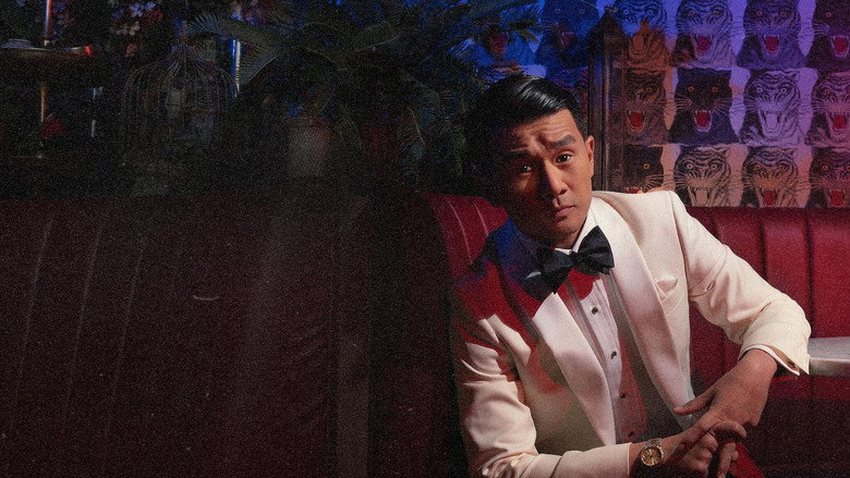 Ronny Chieng mid-performance, bathed in warm stage lighting, a slight smirk playing on his lips as he leans into the mic
