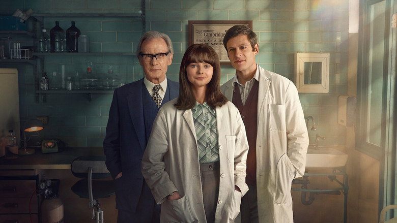 A dimly lit laboratory, glassware catching the light, as Jean Purdy (Thomasin McKenzie) peers into a microscope, her face half in shadow.