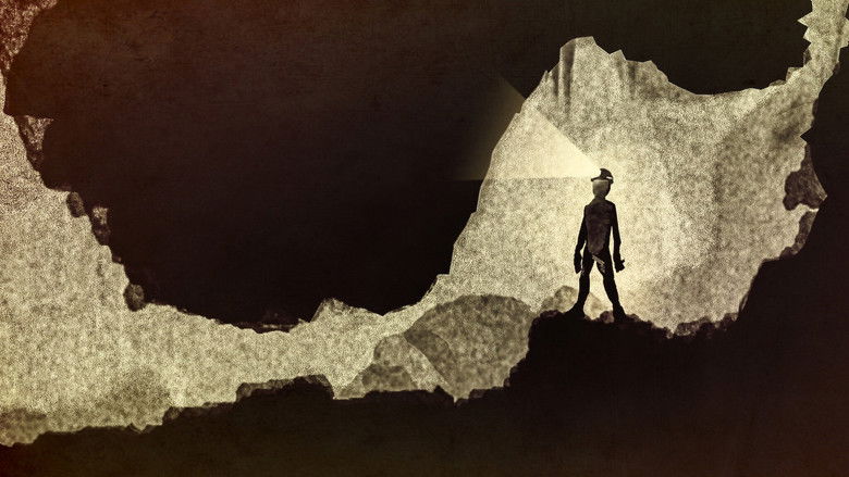 A narrow, dimly lit cave passage, the camera pressed close to the jagged rock walls as a researcher crawls through the tight space.