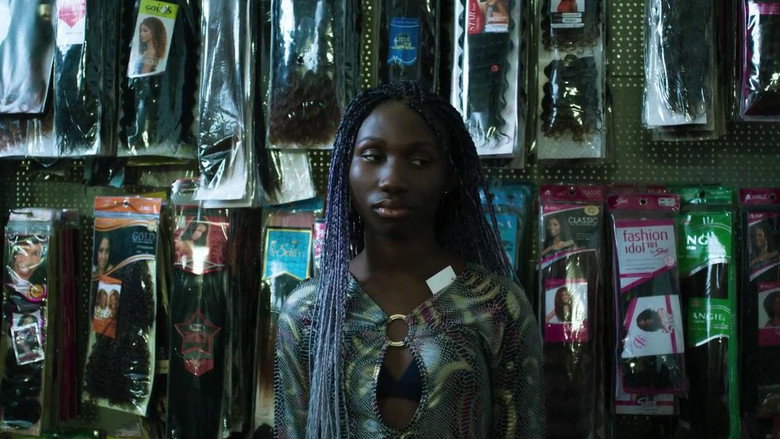 A dimly lit room where Joy sits on a bed, her face half in shadow, staring at something off-camera.