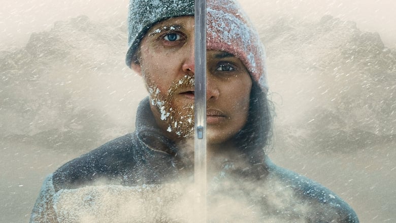 A couple stands in the snow, their breath visible in the cold air, the vast wilderness stretching behind them