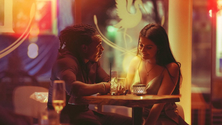 A dimly lit restaurant booth, two people sitting across from each other, one mid-laugh, the other looking uncertain