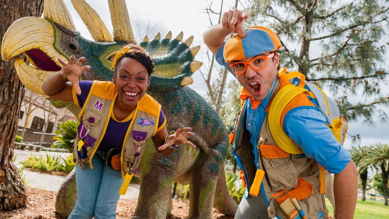 Blippi and Meekah standing in front of a colorful dinosaur exhibit, arms outstretched as if inviting the viewer to join them.