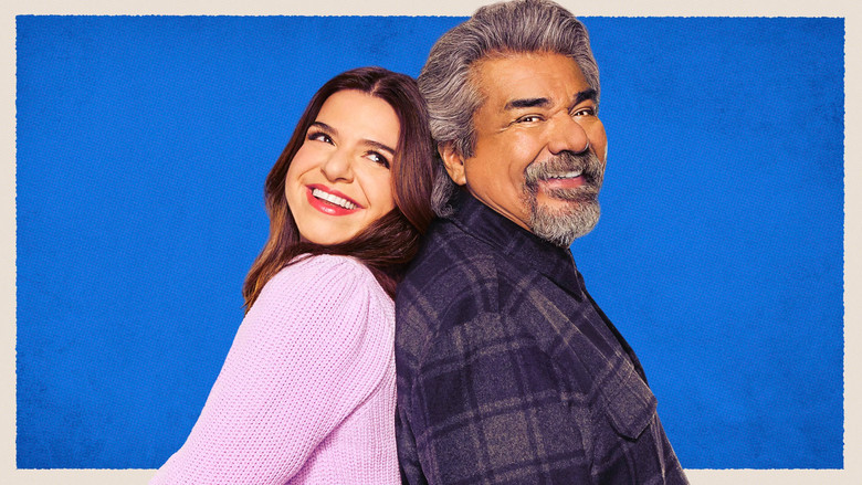A dimly lit living room where George Lopez and Mayan Lopez sit on opposite ends of a couch, their body language stiff but their expressions betraying a flicker of reluctant affection.
