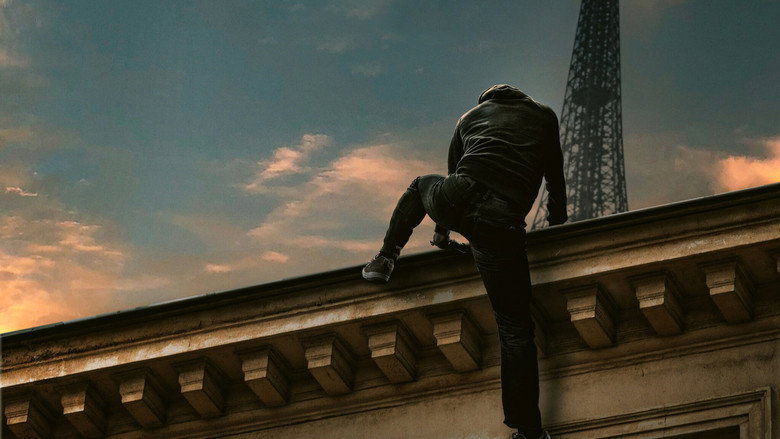 A shadowy figure moves across a Parisian rooftop at night, the city’s lights blurred in the background.