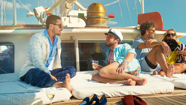 A group of impeccably dressed friends toast with champagne on a rooftop at sunset, the Barcelona skyline shimmering behind them.