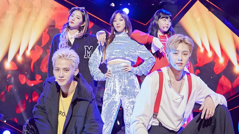 A dimly lit practice room, where a group of trainees stand in a loose circle, their expressions a mix of exhaustion and determination