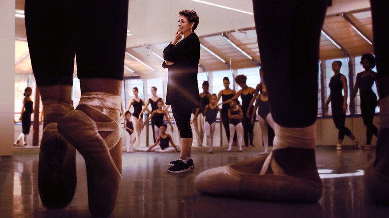 A group of young dancers in vibrant, eclectic costumes mid-performance, their bodies caught in a moment of synchronized motion.