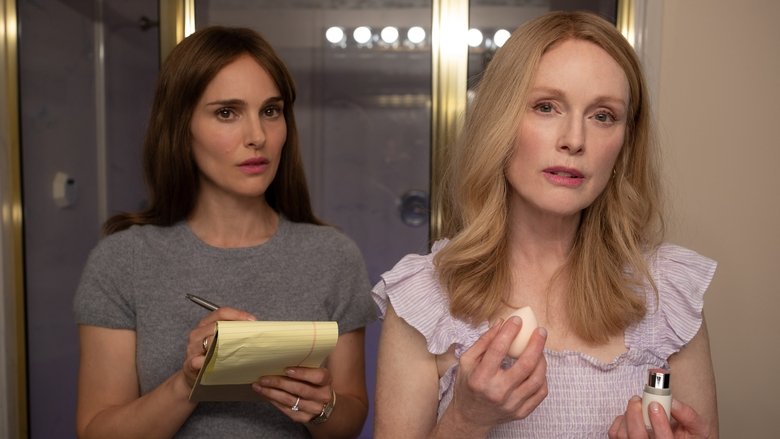 Gracie and Elizabeth sit across from each other at a kitchen table, the tension between them palpable as Gracie offers a plate of cookies with unsettling cheerfulness.