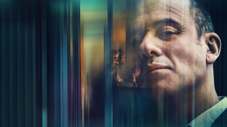 A man in a suit stands in the rain outside a modern apartment building, his reflection distorted in the glass.