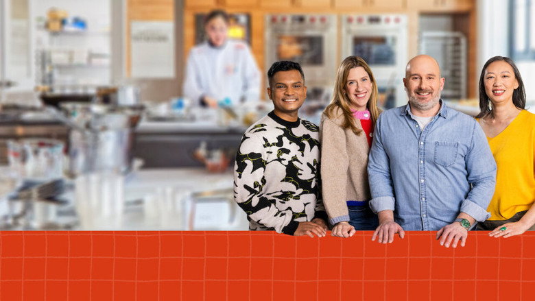 The four hosts stand around a stainless steel counter, smiling at the camera, their expressions a mix of enthusiasm and rehearsed warmth.
