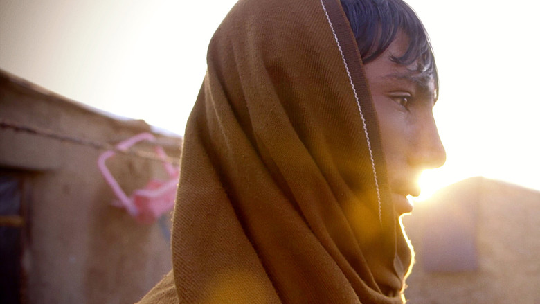 A dusty camp under a vast, pale sky, rows of makeshift shelters stretching into the distance.