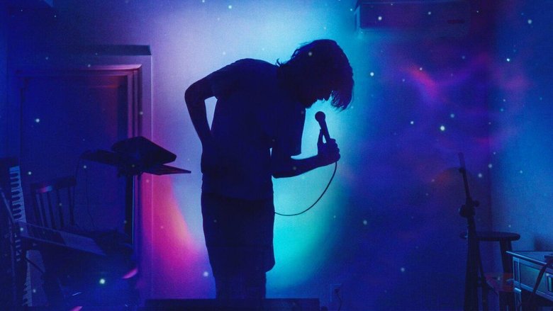 Burnham sitting at a piano, bathed in blue light, his face half in shadow