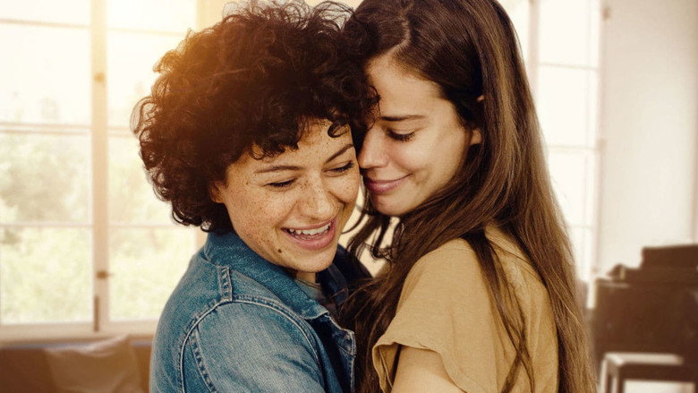 Naima and Sergio lying in bed, tangled in sheets, their faces lit by the soft glow of morning light