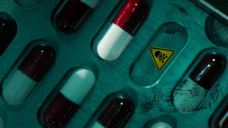 A close-up of a Tylenol bottle with a tamper-evident seal, the plastic collar half-torn, casting a shadow over the label.