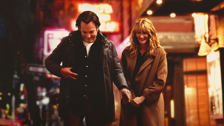 A dimly lit comedy club stage with a single microphone stand