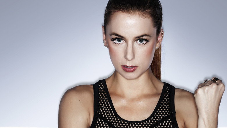Iliza Shlesinger mid-performance, arms outstretched, as if corralling an invisible crowd