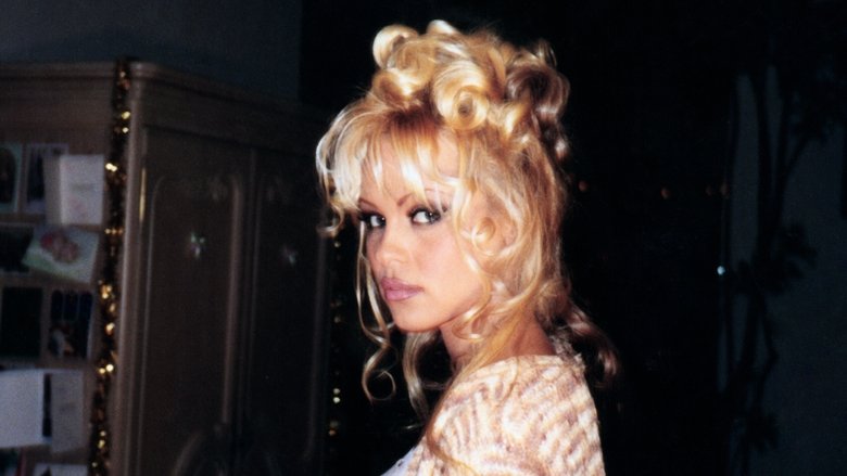 Pamela Anderson sitting in a sunlit room, looking directly at the camera with a faint, contemplative smile